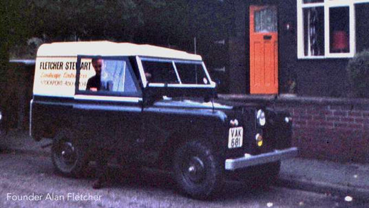 Vintage van with 'Fletcher Stewart' branding parked in front of a house.